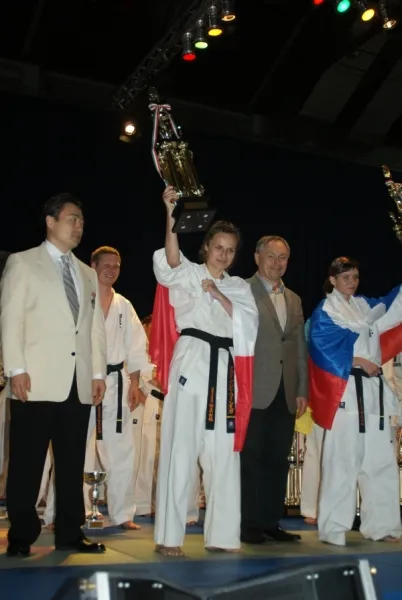 Zawodniczka klubu unosi puchar na podium 26. Wagowych Mistrzostw Europy w Budapeszcie, obok flaga Polski